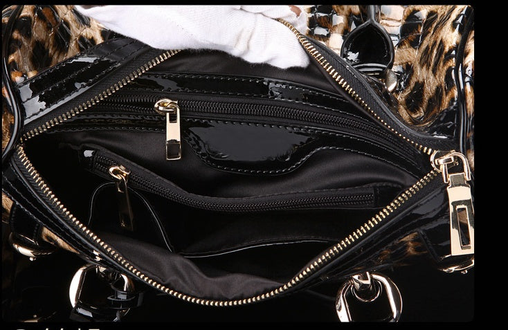 Black handbag with gold zippers and hardware on a patterned background