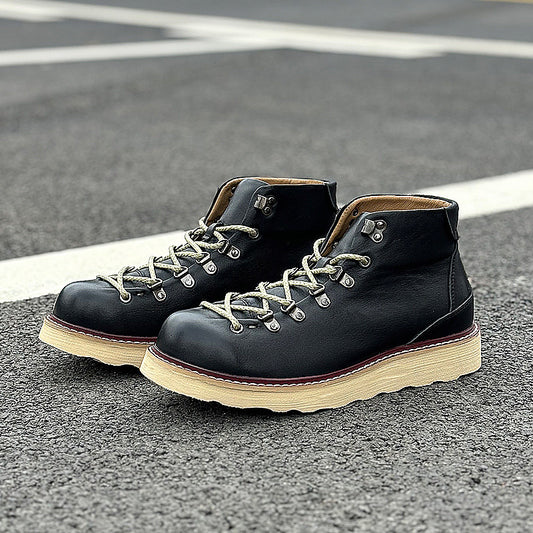 Pair of black leather boots with beige soles on a road surface