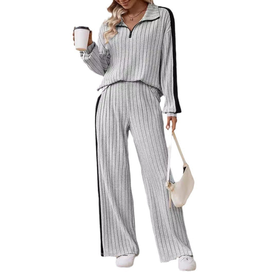 Woman wearing a gray and white striped outfit holding a coffee cup and a beige bag on a white background