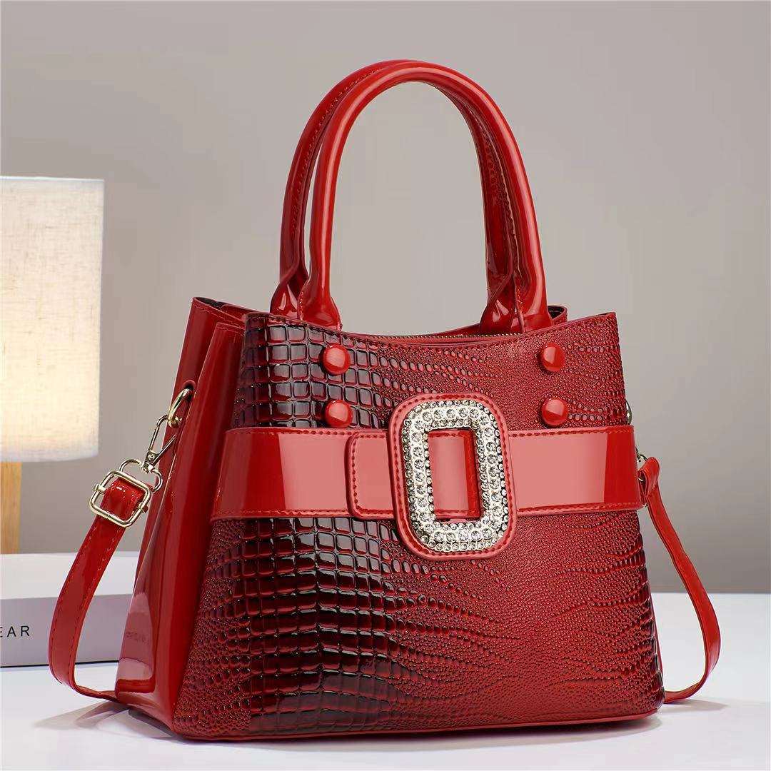 Red handbag with a decorative buckle on a neutral background