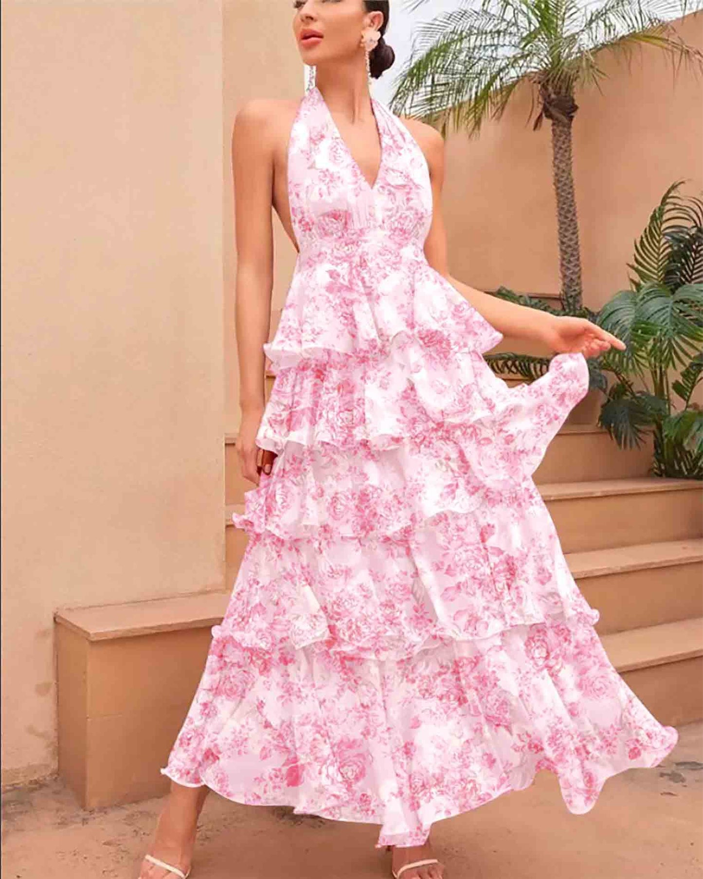 Woman wearing a pink floral dress standing outdoors with a palm tree in the background
