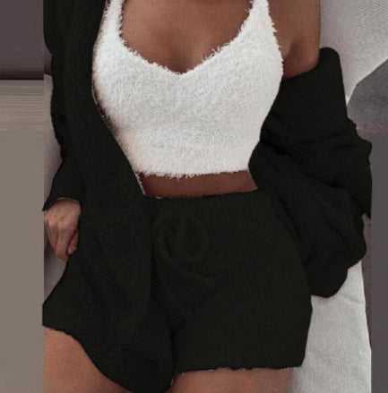 Person wearing a white fuzzy top and black shorts with a blurred background