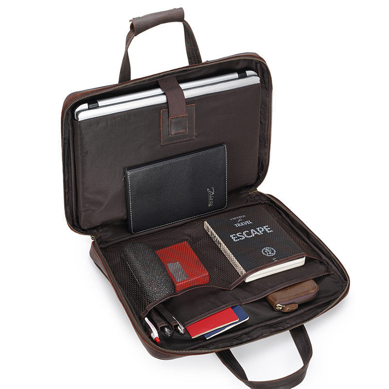 Open brown leather briefcase with various items on a white background