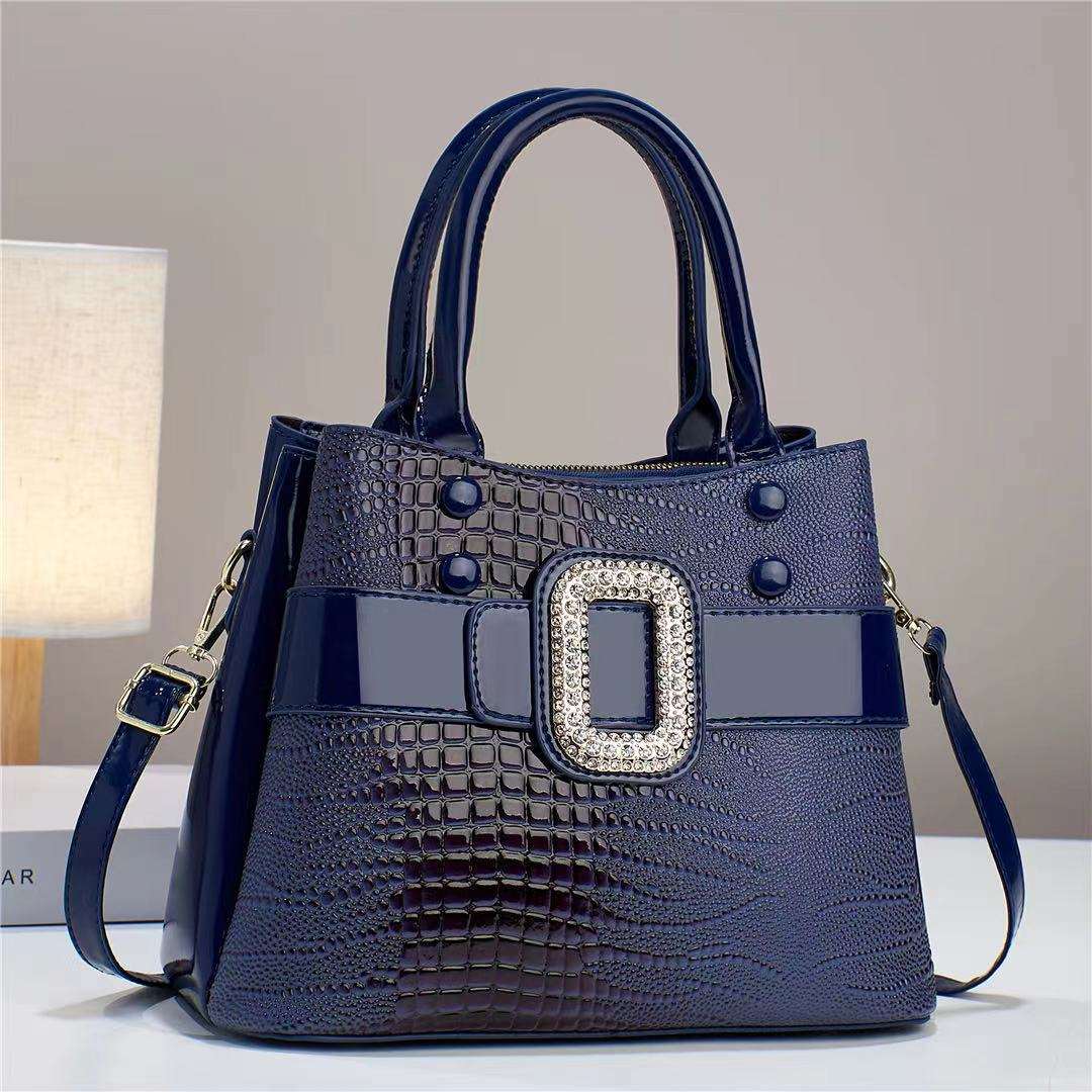 Navy blue handbag with a decorative buckle on a neutral background