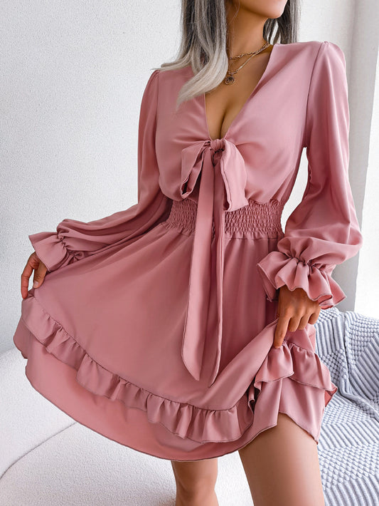 Pink dress with long sleeves and ruffled details worn by a person indoors.