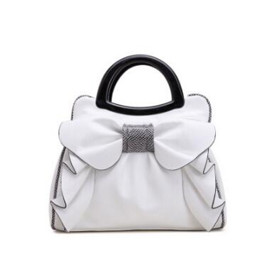 White handbag with a large bow and black handle on a white background