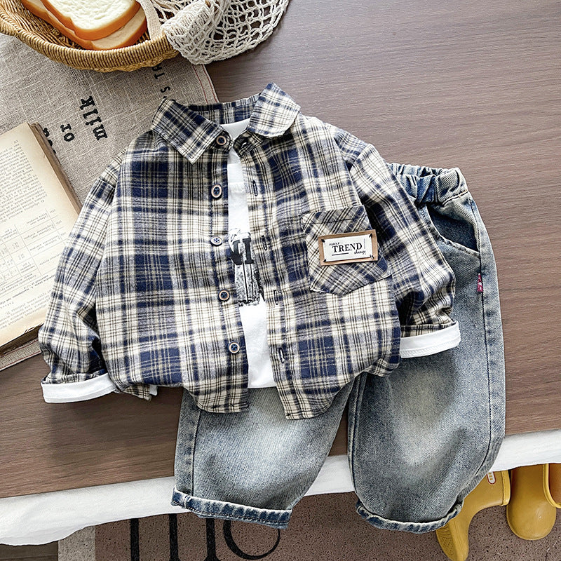 Children's plaid shirt and denim shorts on a wooden surface with a basket and book in the background.