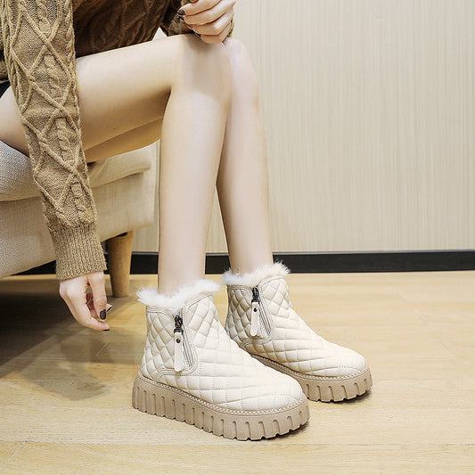 Person wearing white quilted ankle boots with fur trim on a wooden floor.