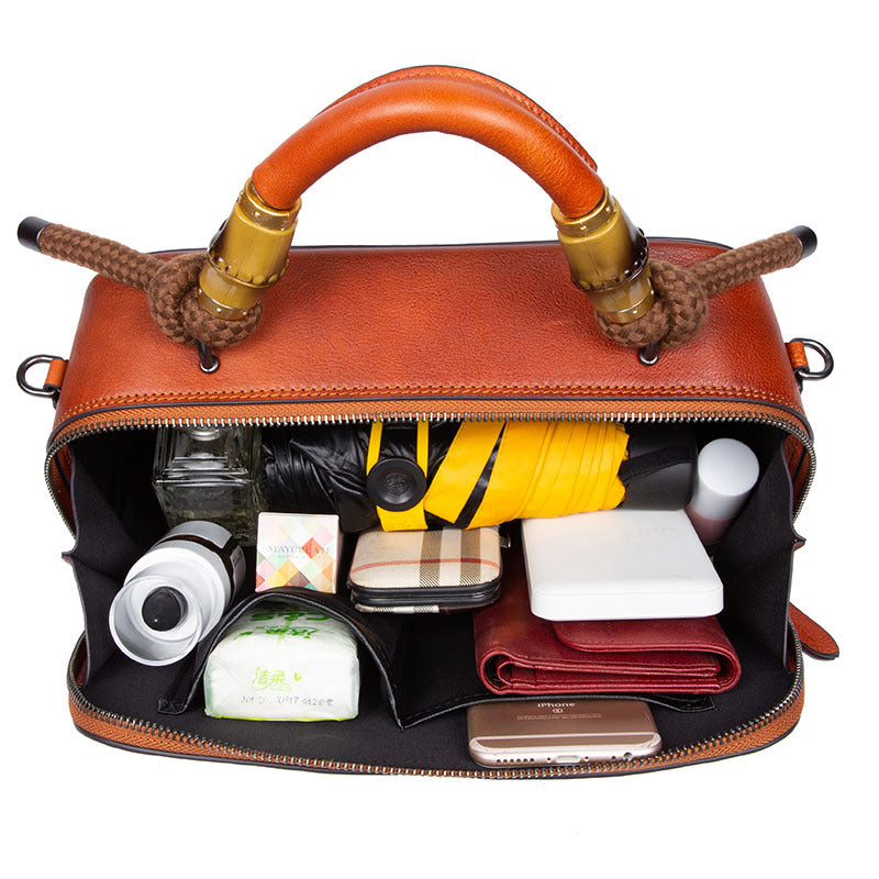 Brown handbag with gold accents filled with various items on a white background