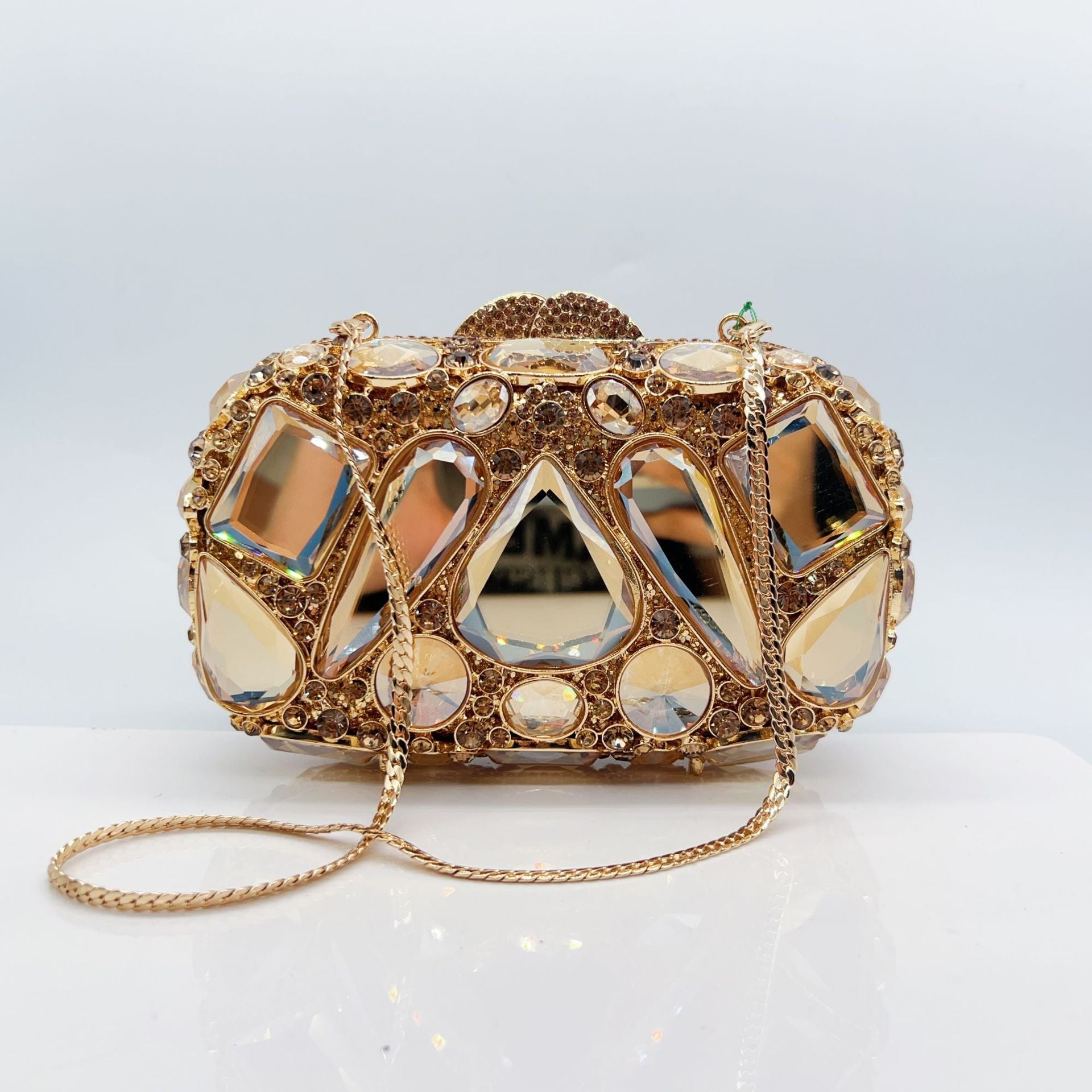 Gold clutch bag with gemstone embellishments on a light gray background