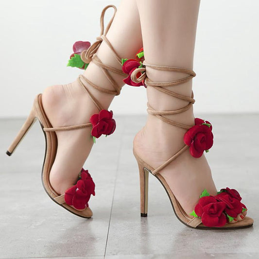 Beige high-heeled sandals with red floral decorations on a light background