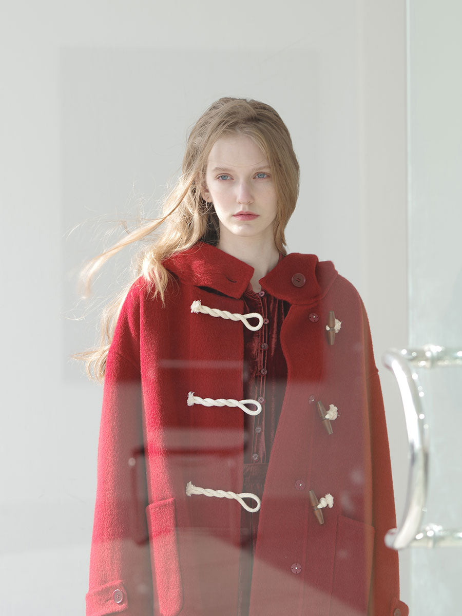 Person wearing a red coat with white buttons against a light background