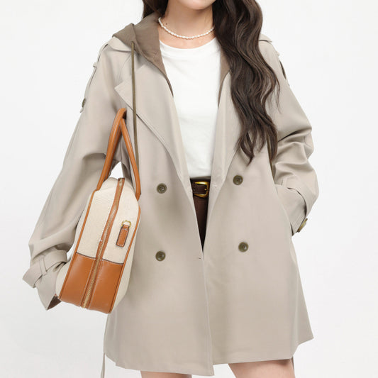 Person wearing a beige trench coat holding a brown and beige handbag on a white background by millivan