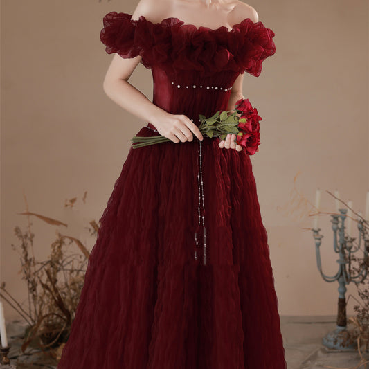 Red off-shoulder dress with floral details held by a person against a neutral background