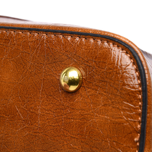 Close-up of a brown leather bag with a gold button on a white background