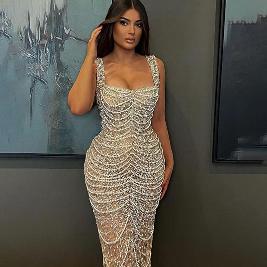 Woman wearing a sparkling silver dress against a gray wall with abstract art.
