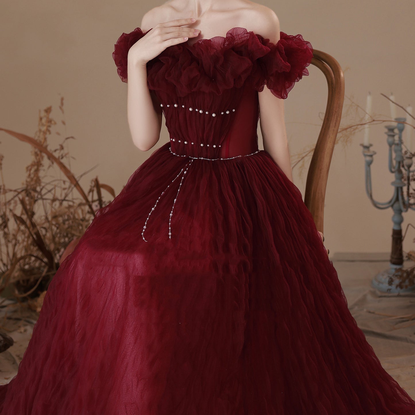 Woman in a burgundy gown sitting on a wooden chair with a vintage background