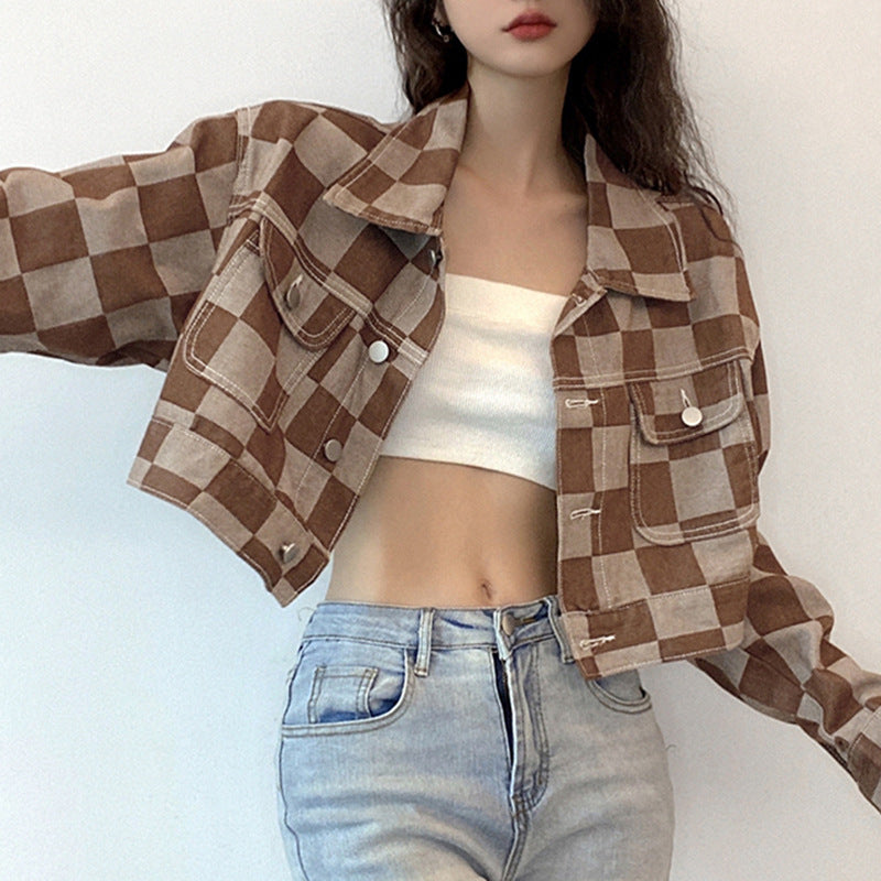 Person wearing a brown checkered jacket, white top, and light blue jeans on a white background