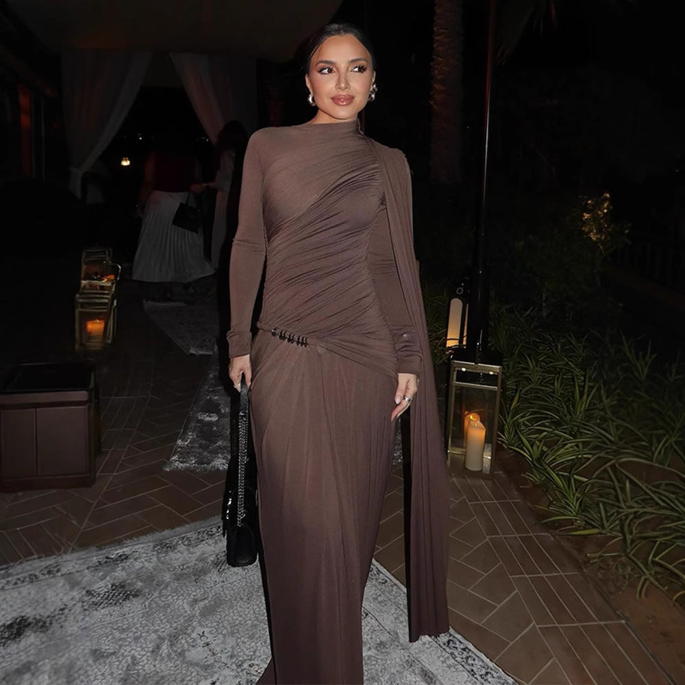 Woman in a brown dress standing in an outdoor setting with candles and plants.