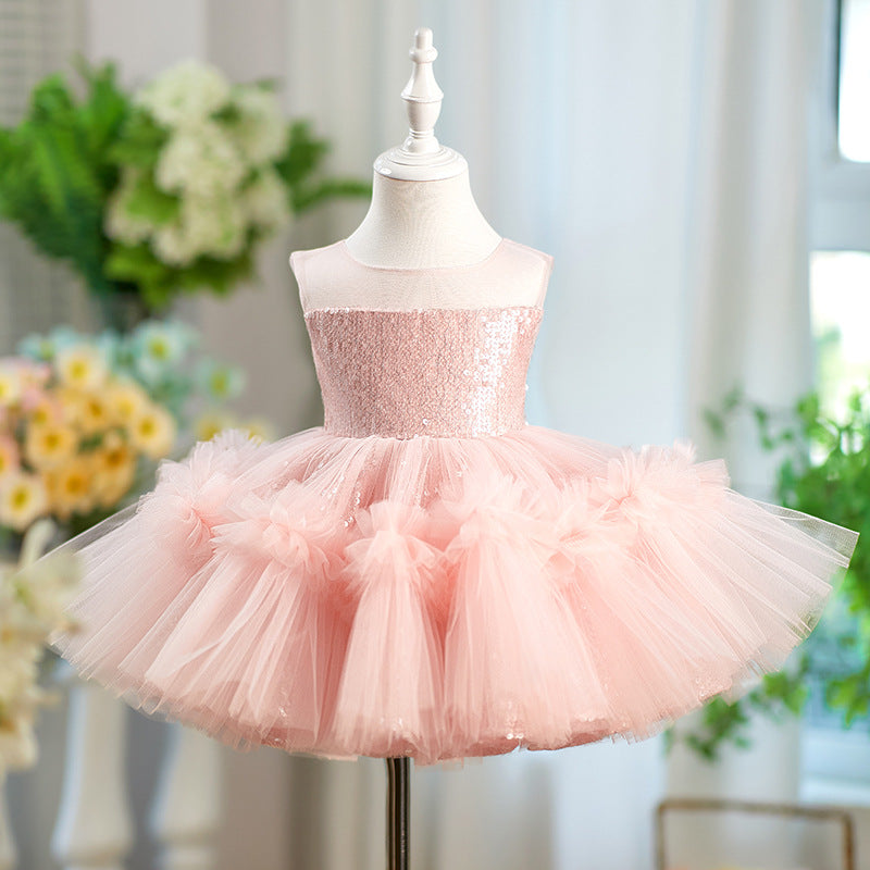 A light pink children's party dress displayed on a white mannequin dress form. The dress features a sparkly sequined strapless bodice and a voluminous tulle tutu skirt with ruffled details.