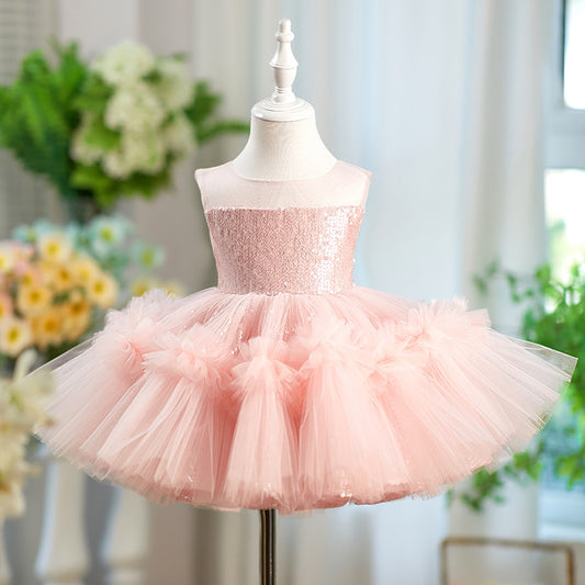 A light pink children's party dress displayed on a white mannequin dress form. The dress features a sparkly sequined strapless bodice and a voluminous tulle tutu skirt with ruffled details.