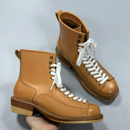 Pair of brown leather boots with white laces on a gray background