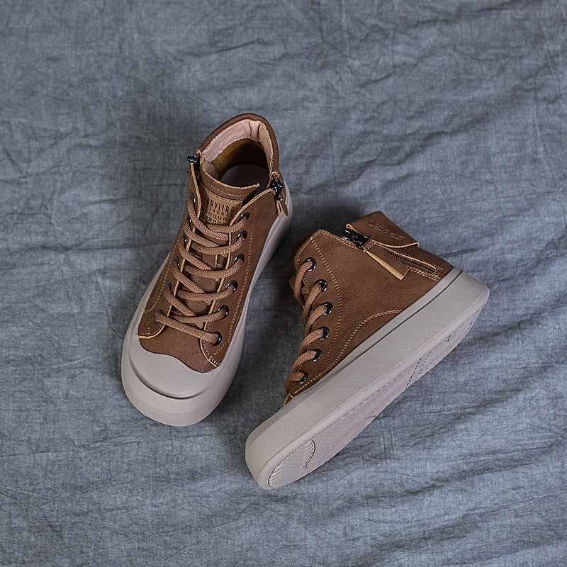 A pair of brown high-top lace-up sneakers with side zippers and thick off-white soles, arranged on a textured gray fabric background.
