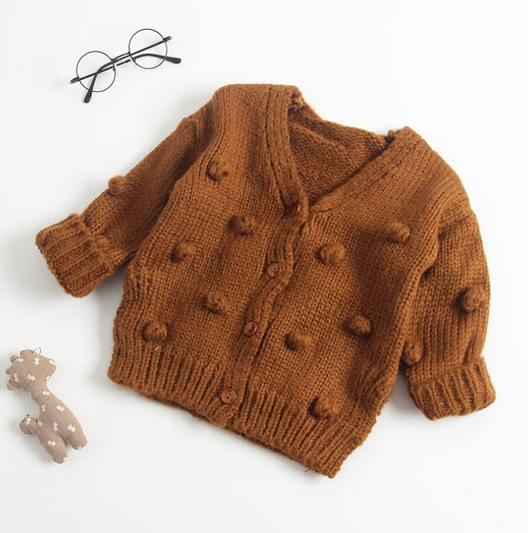 Brown knitted cardigan with pom-poms on a white background