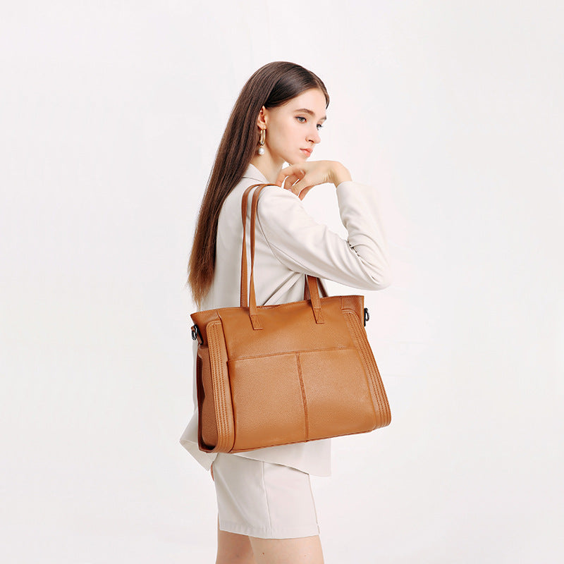 Woman holding a brown leather tote bag against a white background