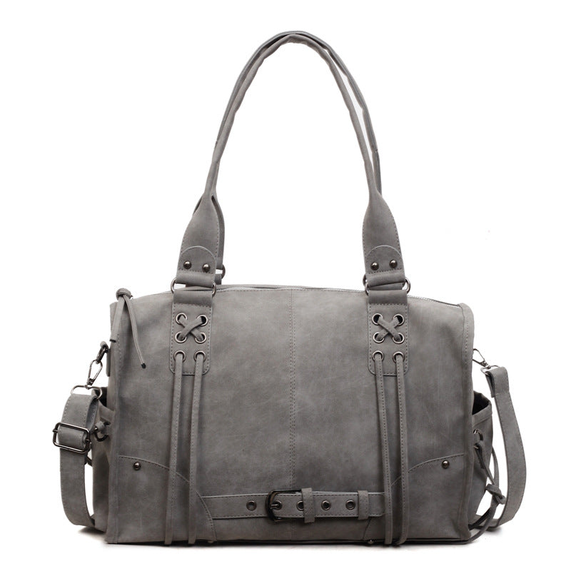 Gray leather bag with decorative straps on a white background