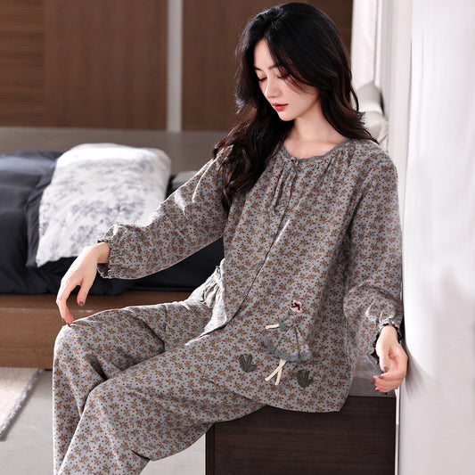 Woman wearing a floral pajama set sitting on a bed in a bedroom.