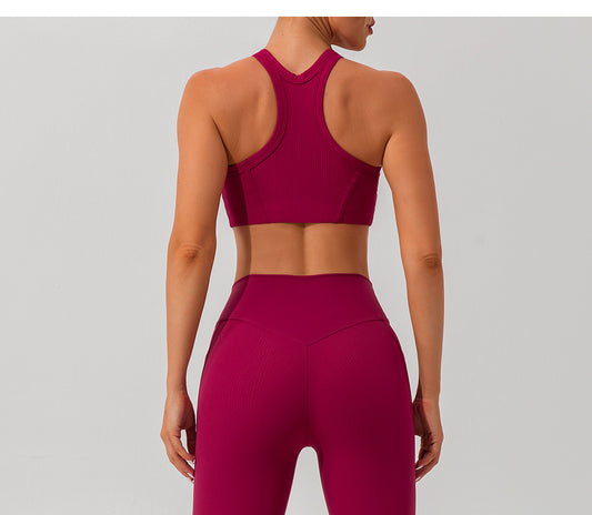Person wearing a maroon sports bra and leggings on a light gray background