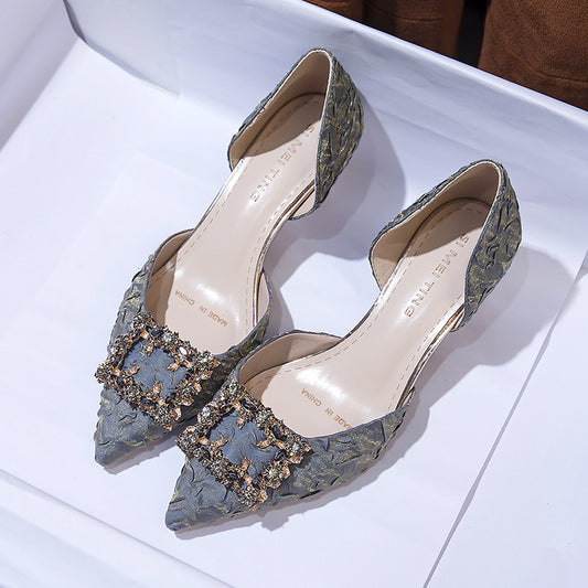 Pair of gray lace high heels with embellishments on a white surface
