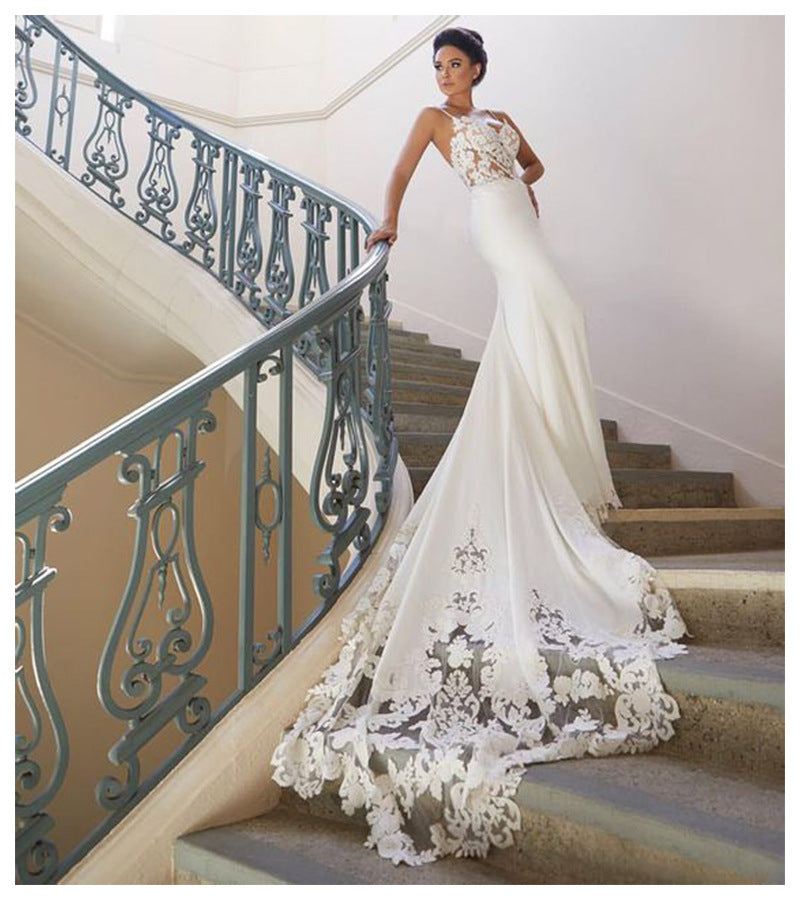 Woman in a white wedding dress with floral details standing on a staircase.