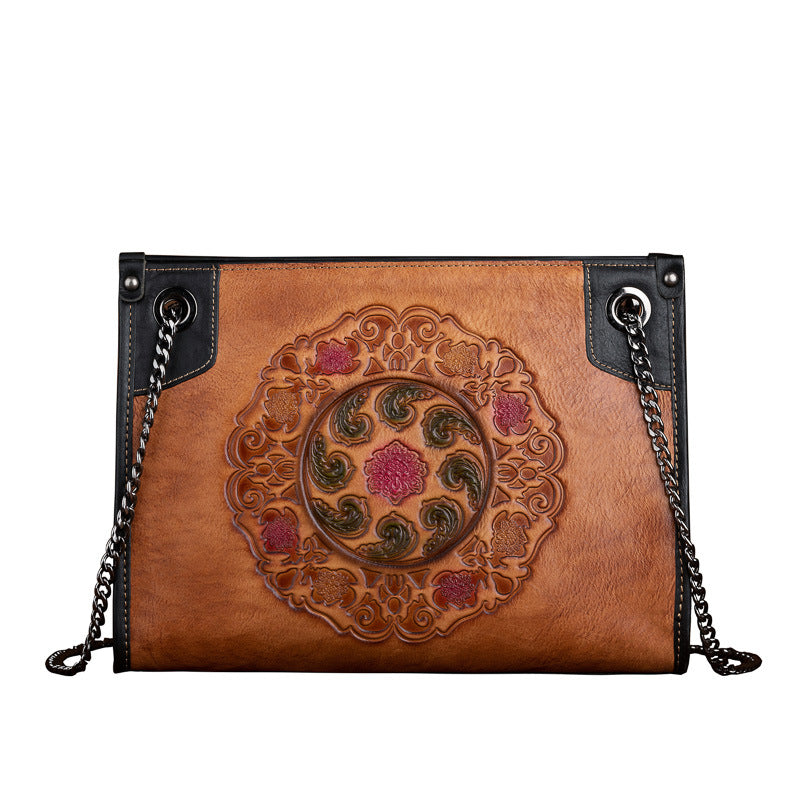 Brown leather handbag with decorative embossing on a white background