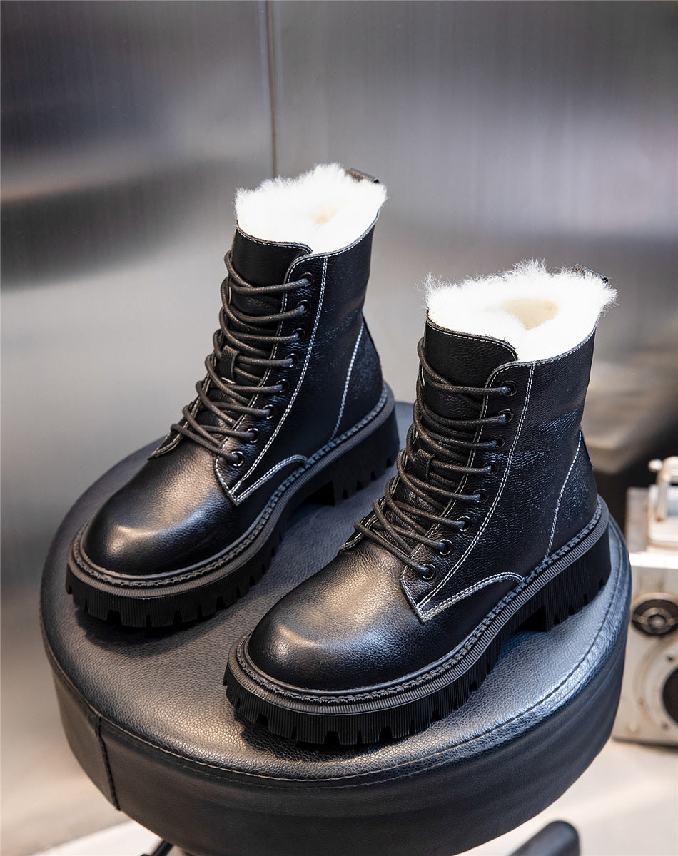 Black leather boots with white fur lining on a black stool against a neutral background