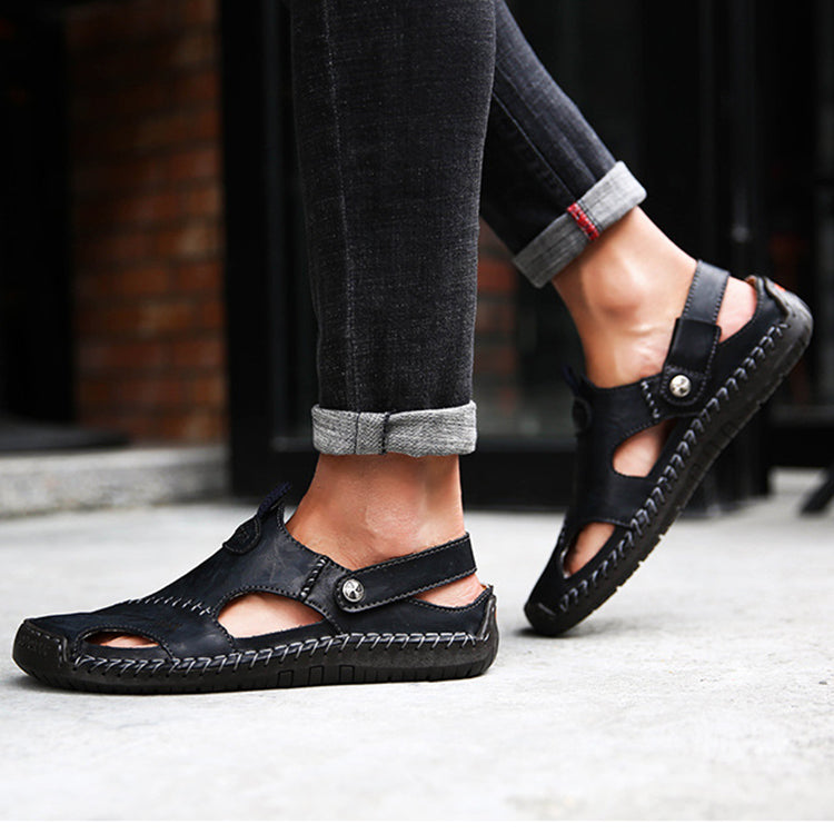 Black sandals worn with rolled-up jeans on a blurred background
