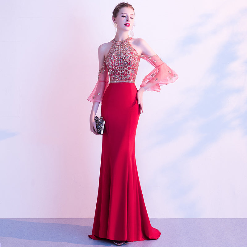 Woman wearing a red evening gown with a beaded top against a light background