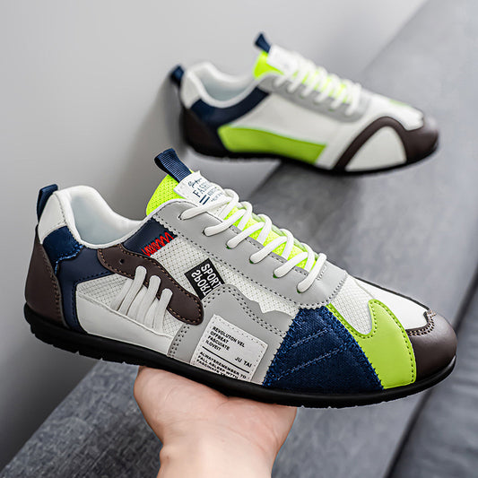 Multicolored sneaker held in hand with another sneaker in the background on a gray surface