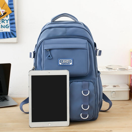Blue backpack with EXIDE logo on a desk next to a tablet and laptop.