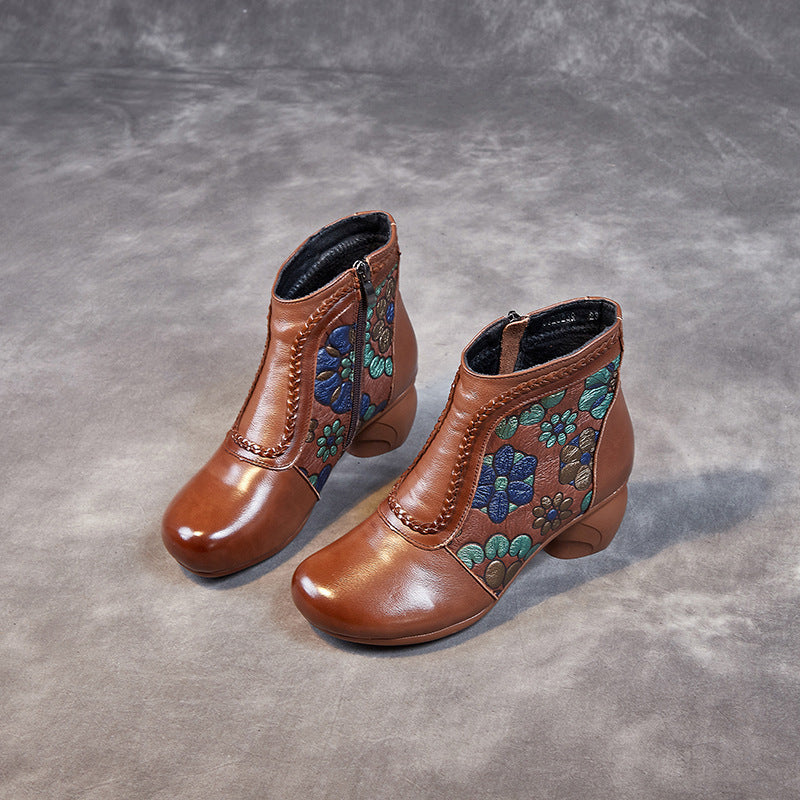 Pair of brown ankle boots with floral embroidery on a gray background