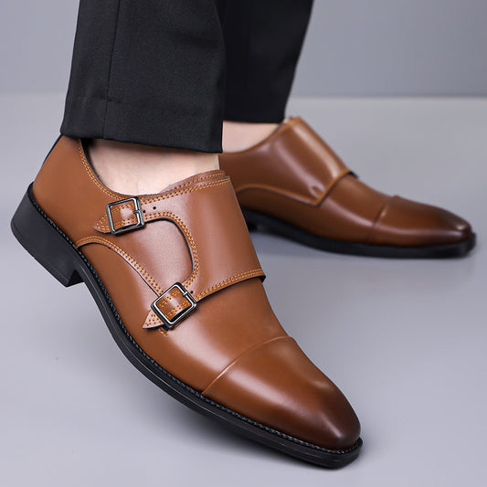 Brown leather shoes with buckles worn by a person on a gray background
