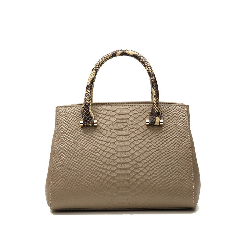 Beige handbag with snake skin texture and braided handle on a white background