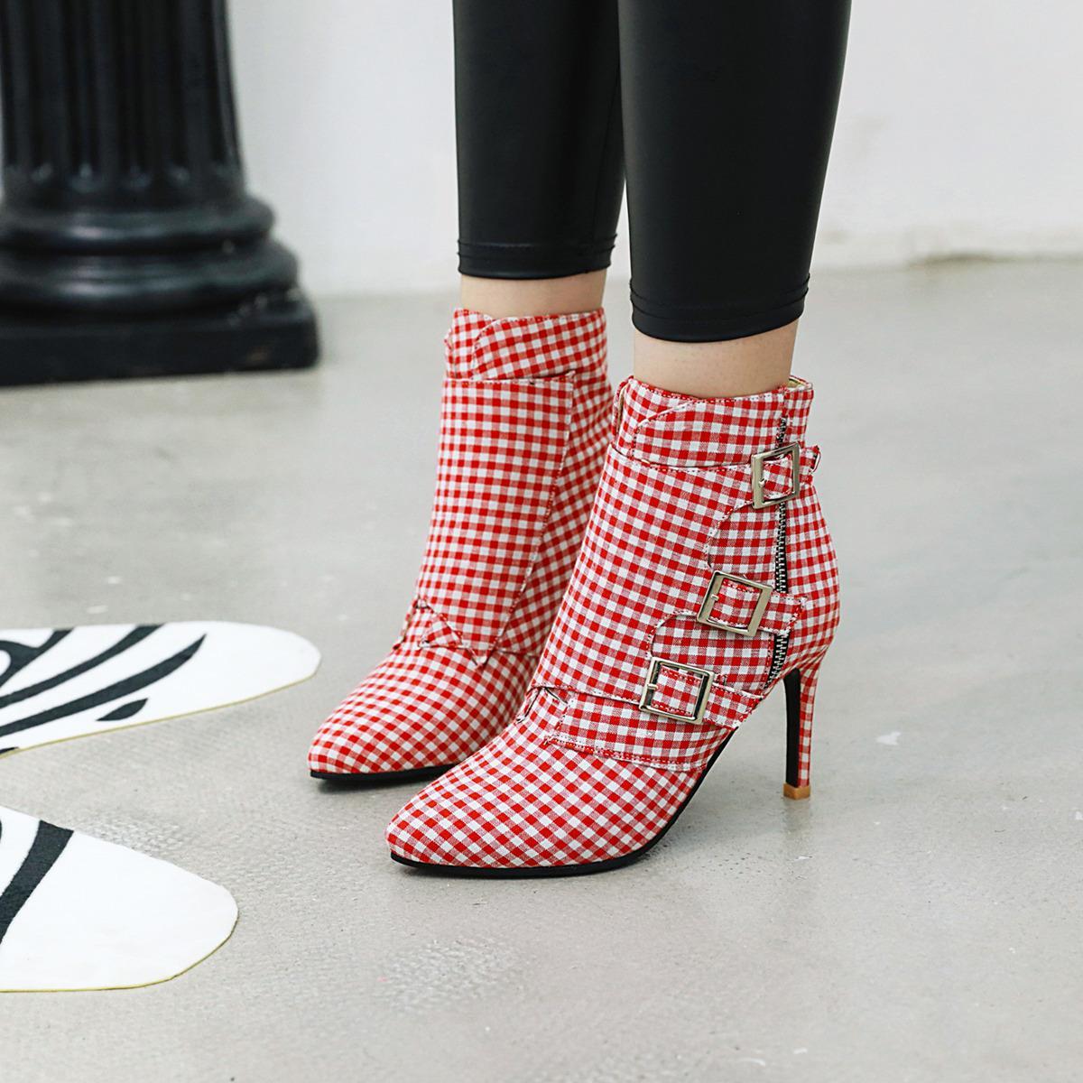 Red and white checkered high-heeled boots with buckles on a light gray floor.