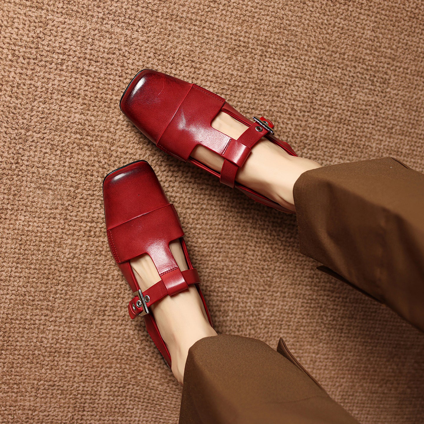 Red shoes worn on a brown textured surface