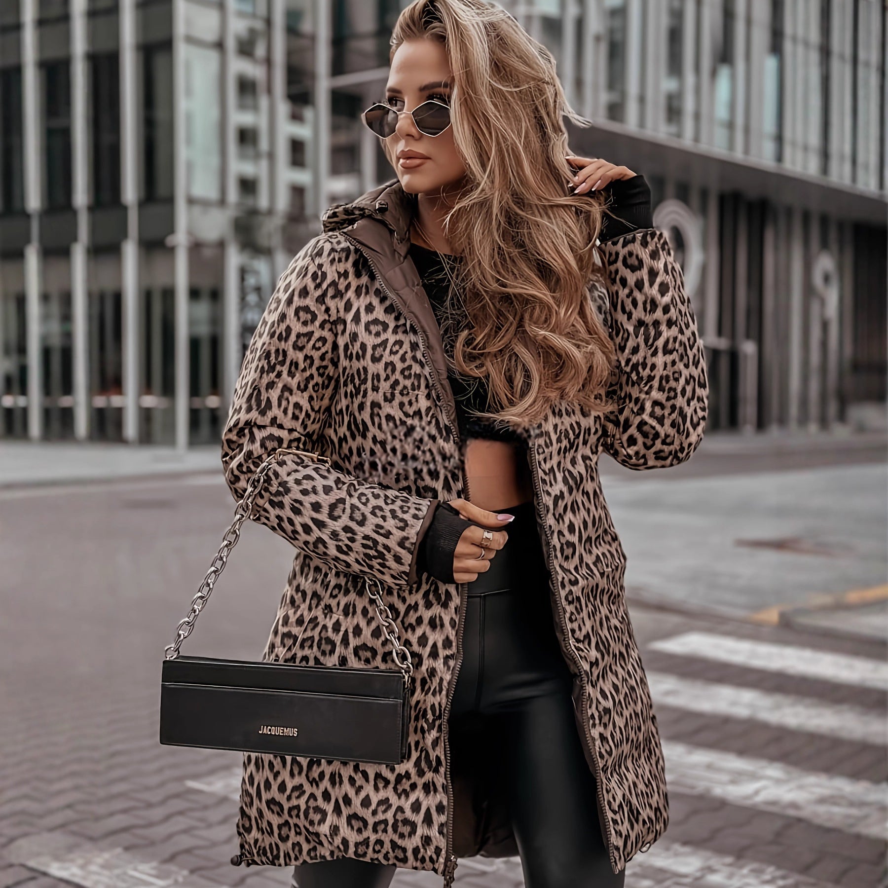 Woman in leopard print coat holding a black handbag on a city street.