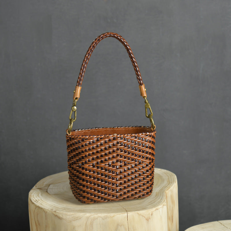 Woven brown handbag with a handle on a wooden block against a gray background
