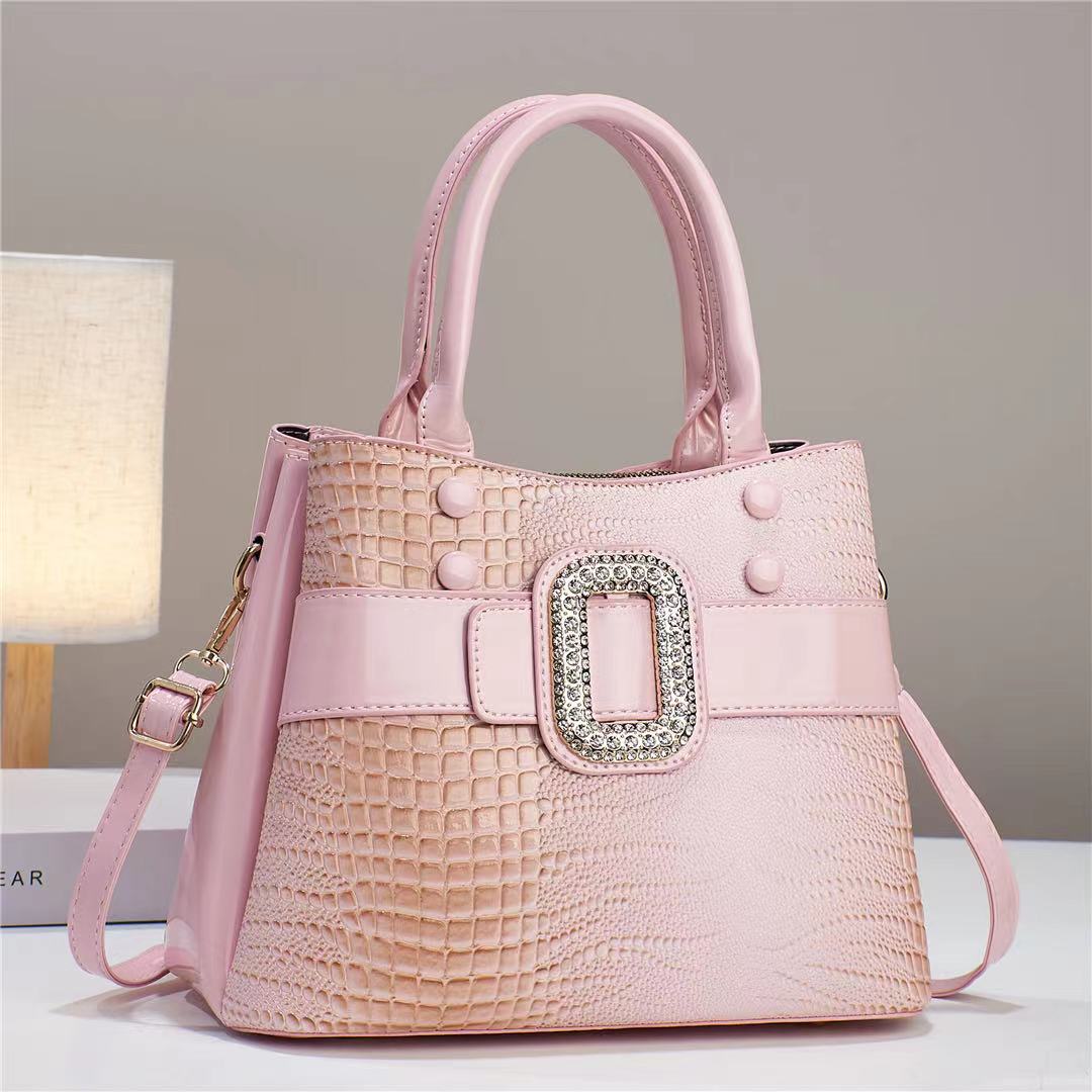 Pink handbag with a decorative buckle on a neutral background
