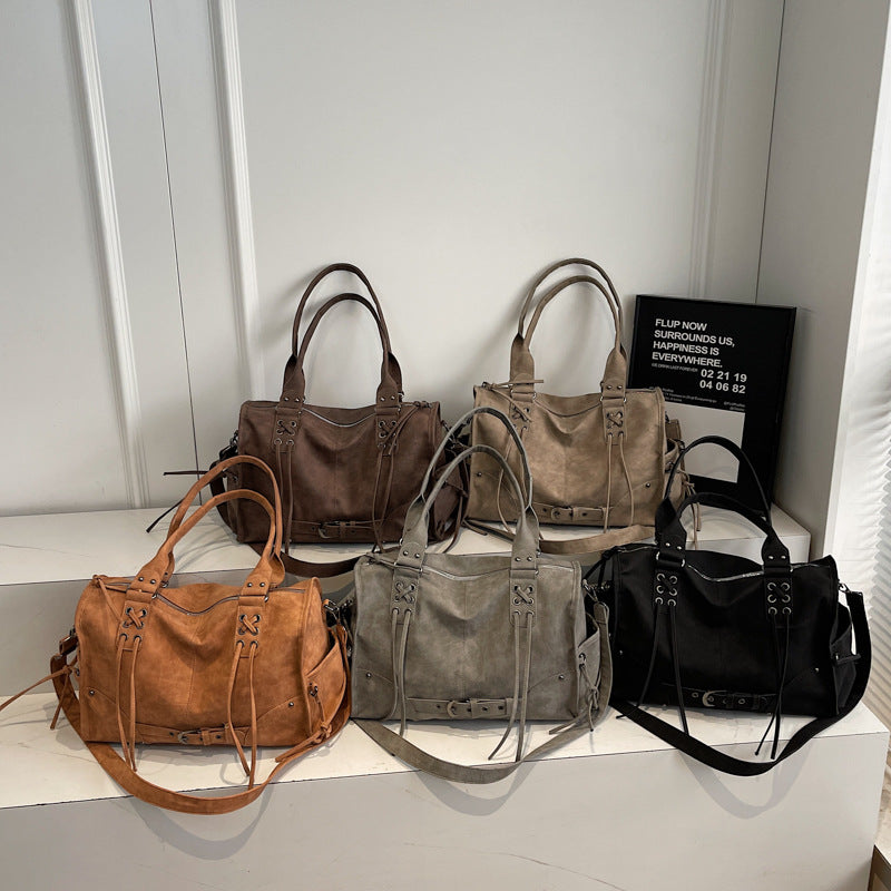 Five handbags in brown, gray, and black on a white surface with a neutral background.
