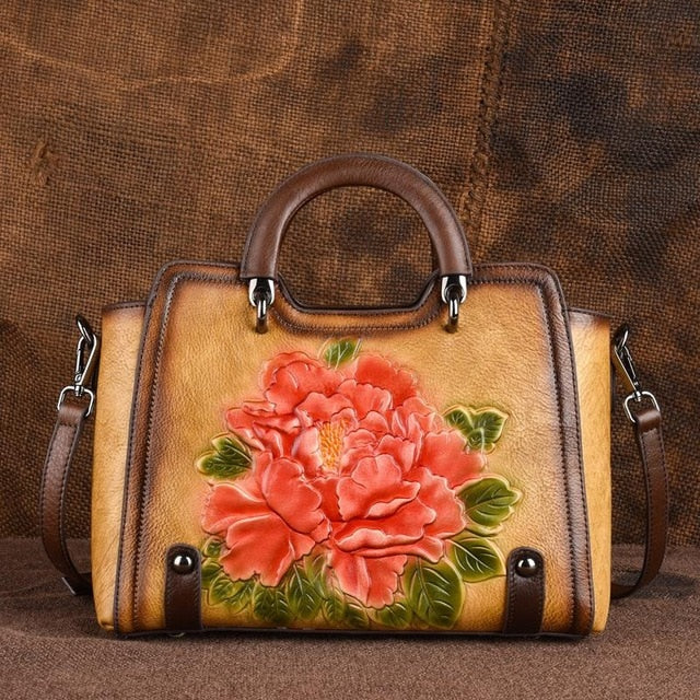 Brown leather handbag with floral design on a brown background